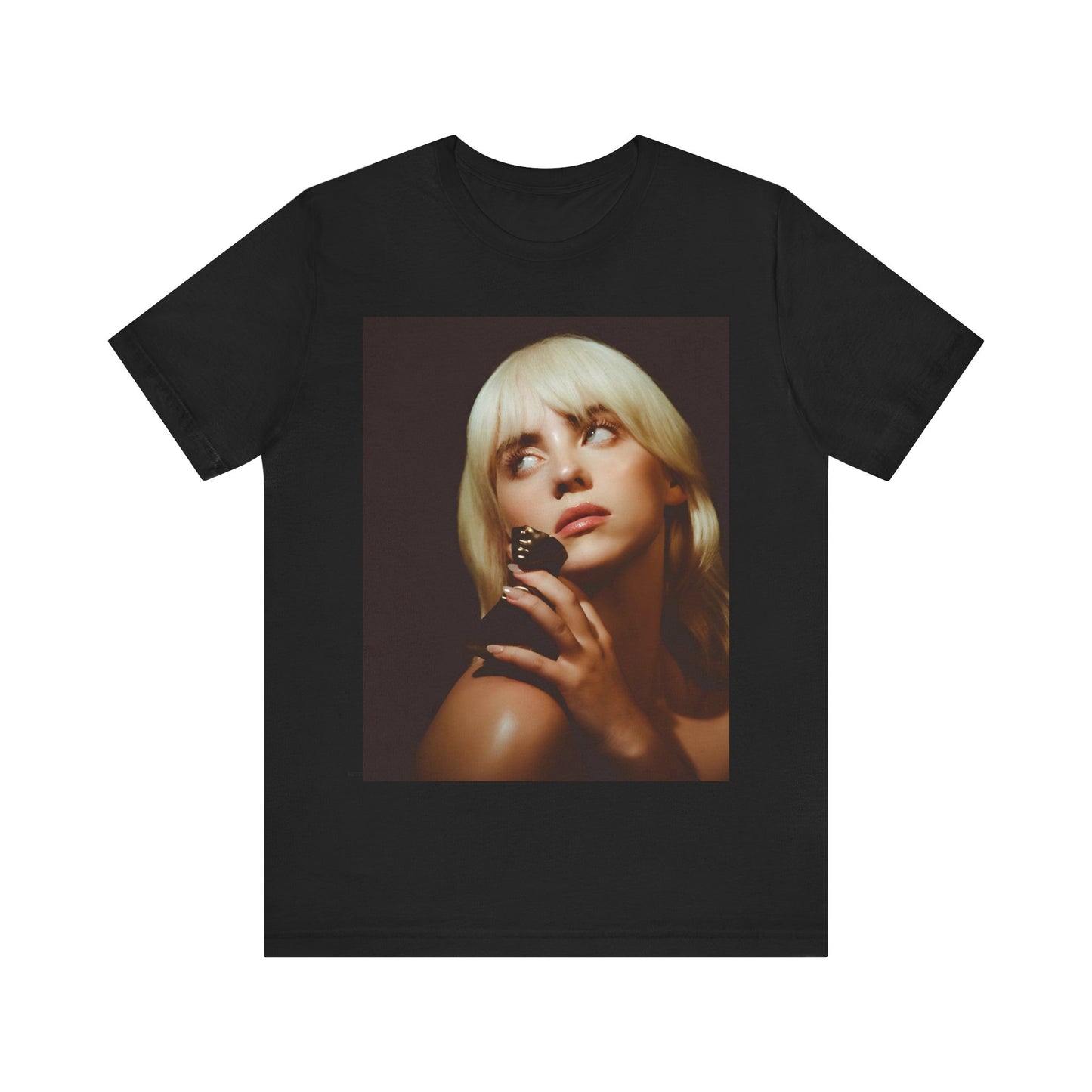 A soft, close-up portrait of Billie Eilish with dark hair looking down thoughtfully, printed on a graphic t-shirt.