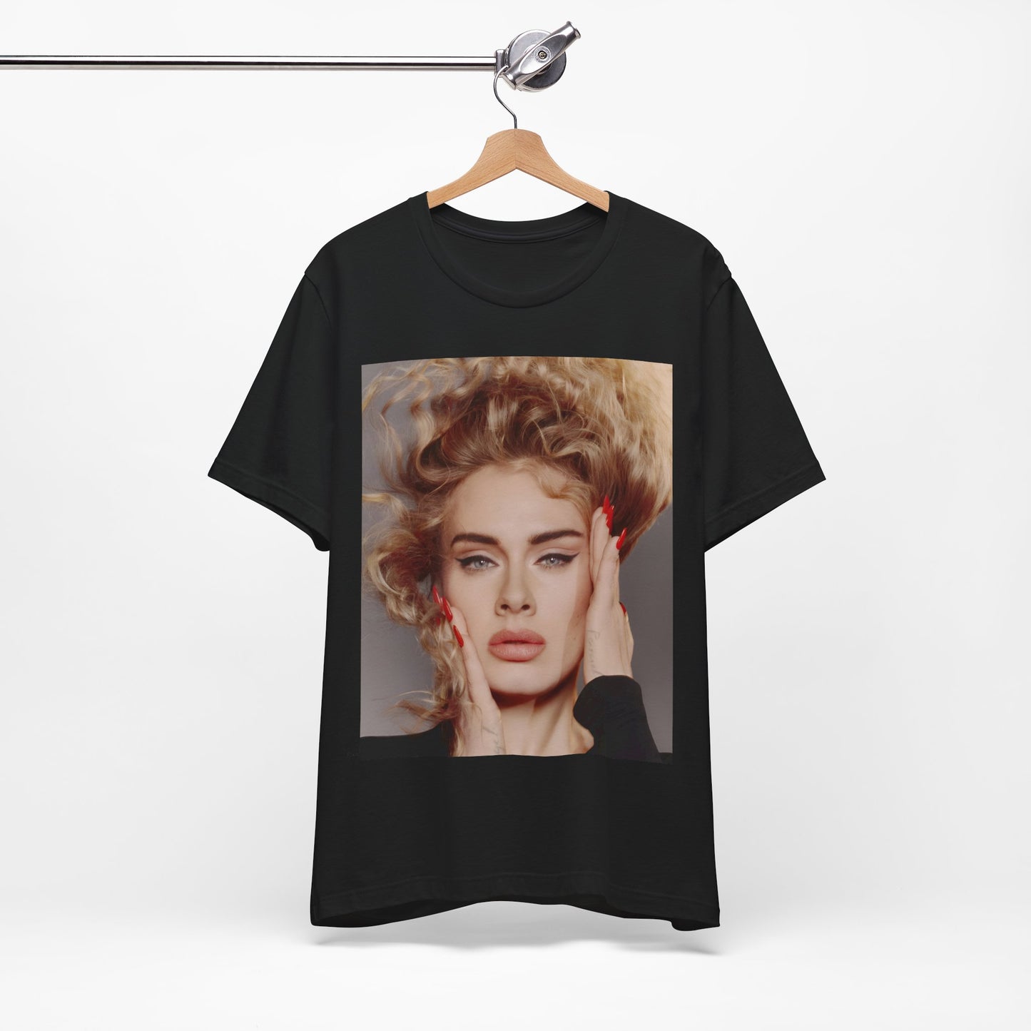 A black graphic t-shirt featuring a detailed, artistic black and white portrait of Adele with her hair dramatically caught in a breeze around her face and her hands gently placed on her cheeks.