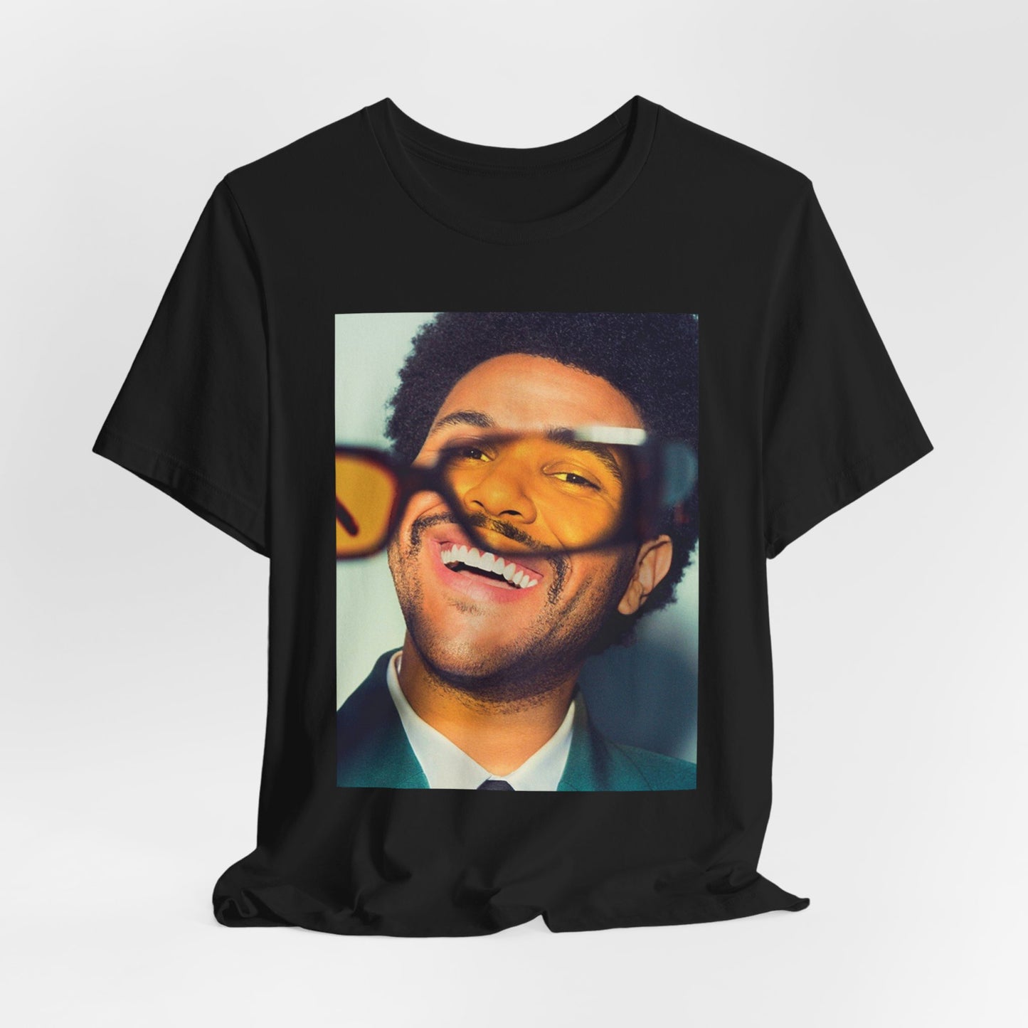 A black graphic t-shirt featuring a bold graphic of The Weeknd as a pop superstar.
