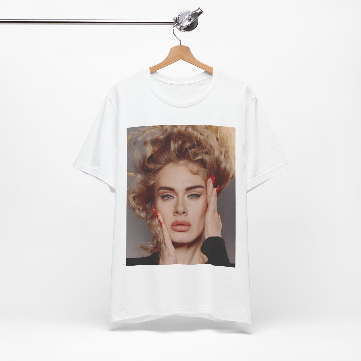 A black graphic t-shirt featuring a detailed, artistic black and white portrait of Adele with her hair dramatically caught in a breeze around her face and her hands gently placed on her cheeks.