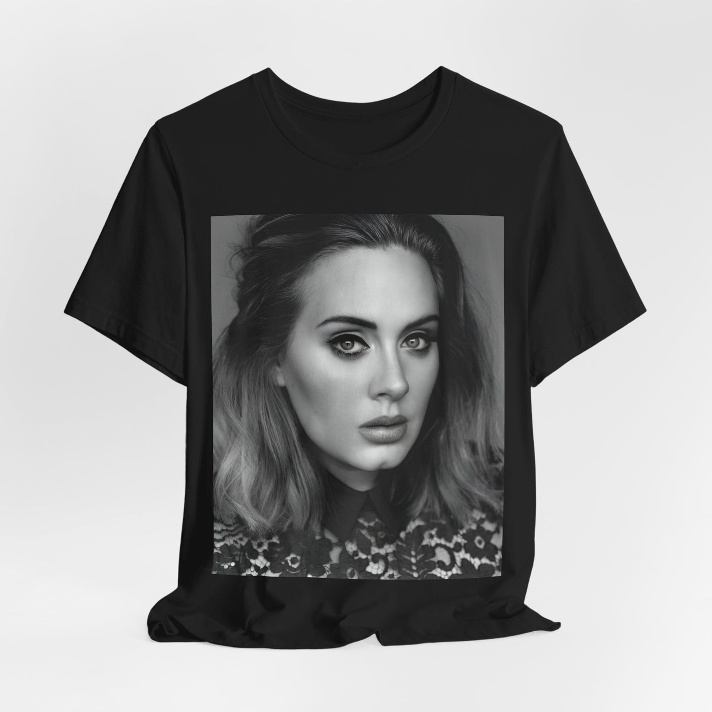 A black graphic t-shirt featuring a classic black and white, monochrome portrait of Adele, showing her with a serene or thoughtful expression.