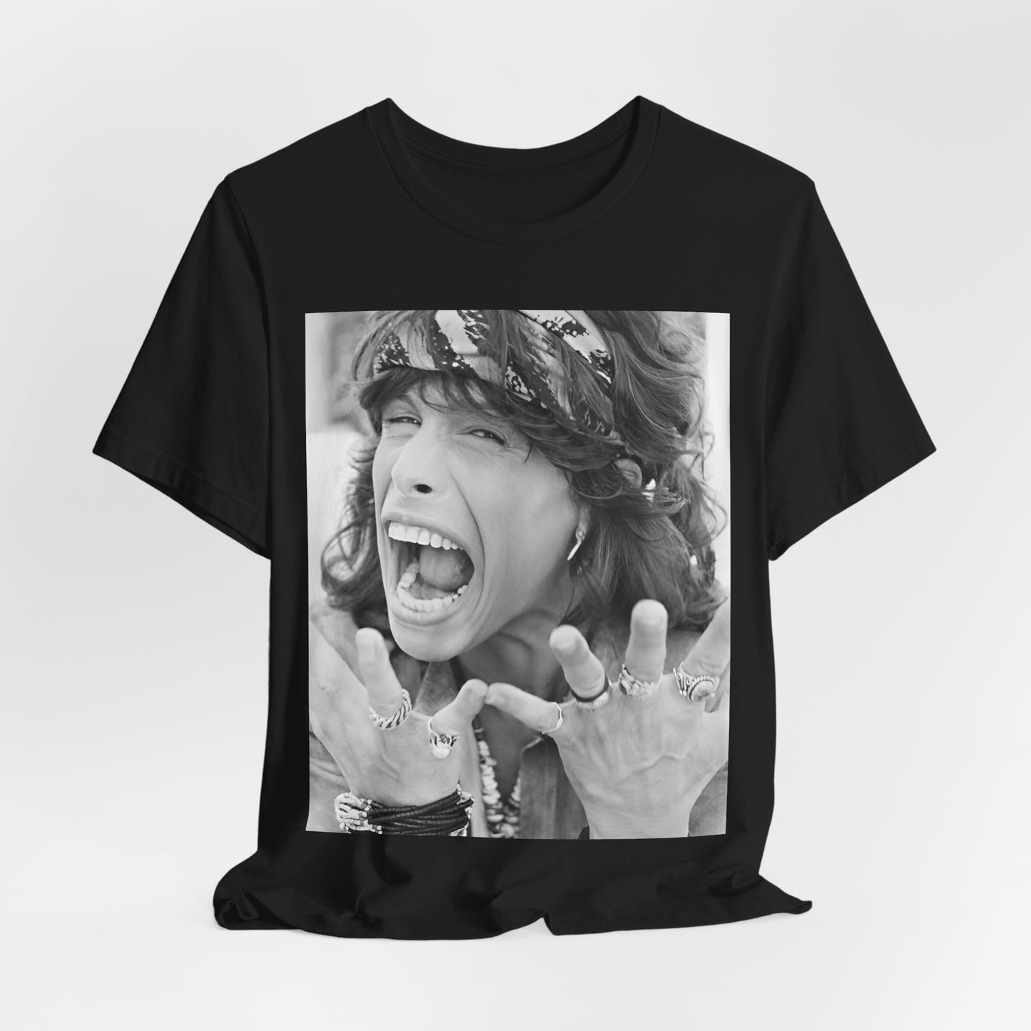 A black graphic t-shirt featuring a candid, dynamic photo of Aerosmith band members on tour in the 1970s, possibly showing action or interaction on stage or backstage.