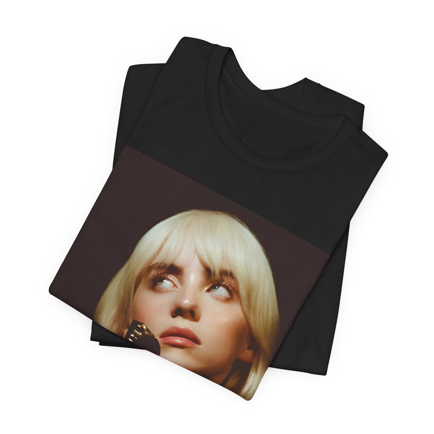 A soft, close-up portrait of Billie Eilish with dark hair looking down thoughtfully, printed on a graphic t-shirt.