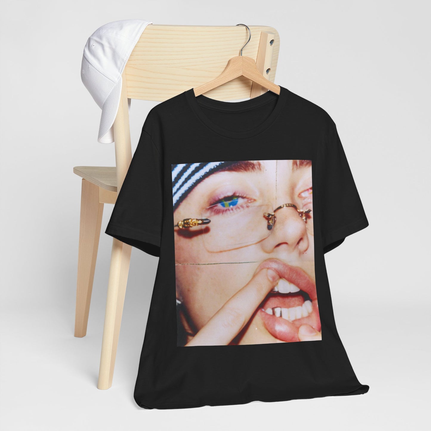 A direct, unfiltered, close-up portrait of Billie Eilish with dark hair looking straight at the camera, printed on a t-shirt.