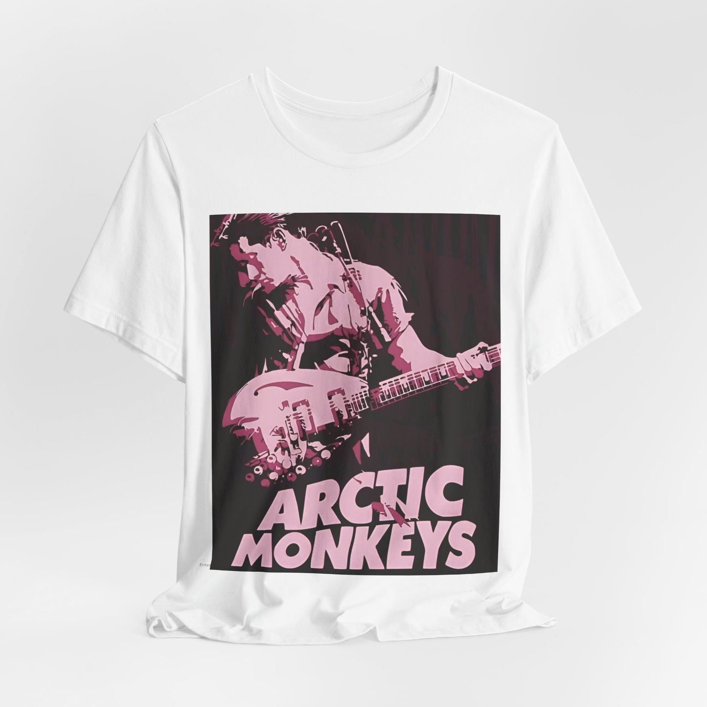 A black graphic t-shirt featuring the Arctic Monkeys logo in a prominent pink color, creating an aesthetic look.