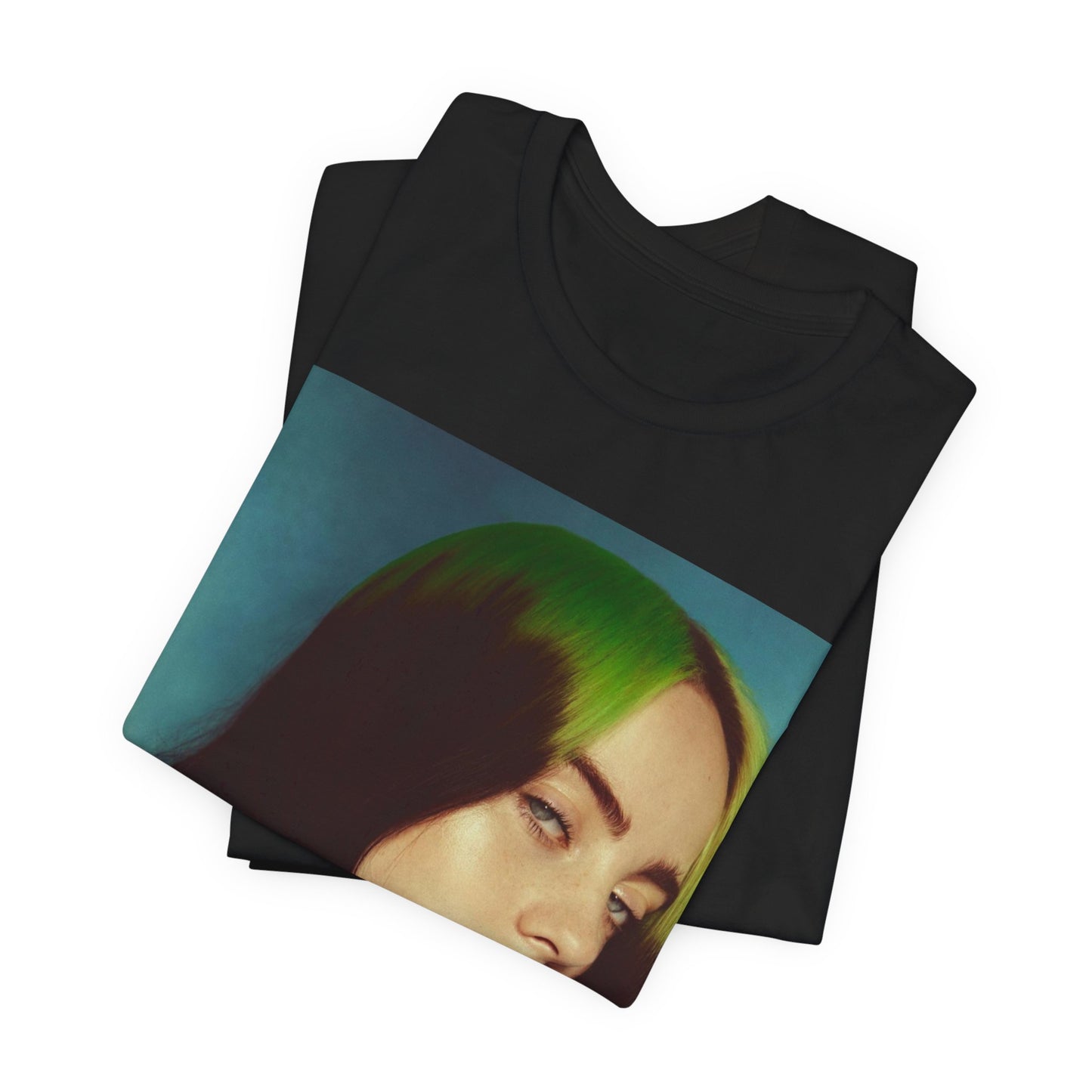 A close-up portrait of Billie Eilish with her signature green-root and black hair, wearing a blue and red sweater, printed on a graphic t-shirt.