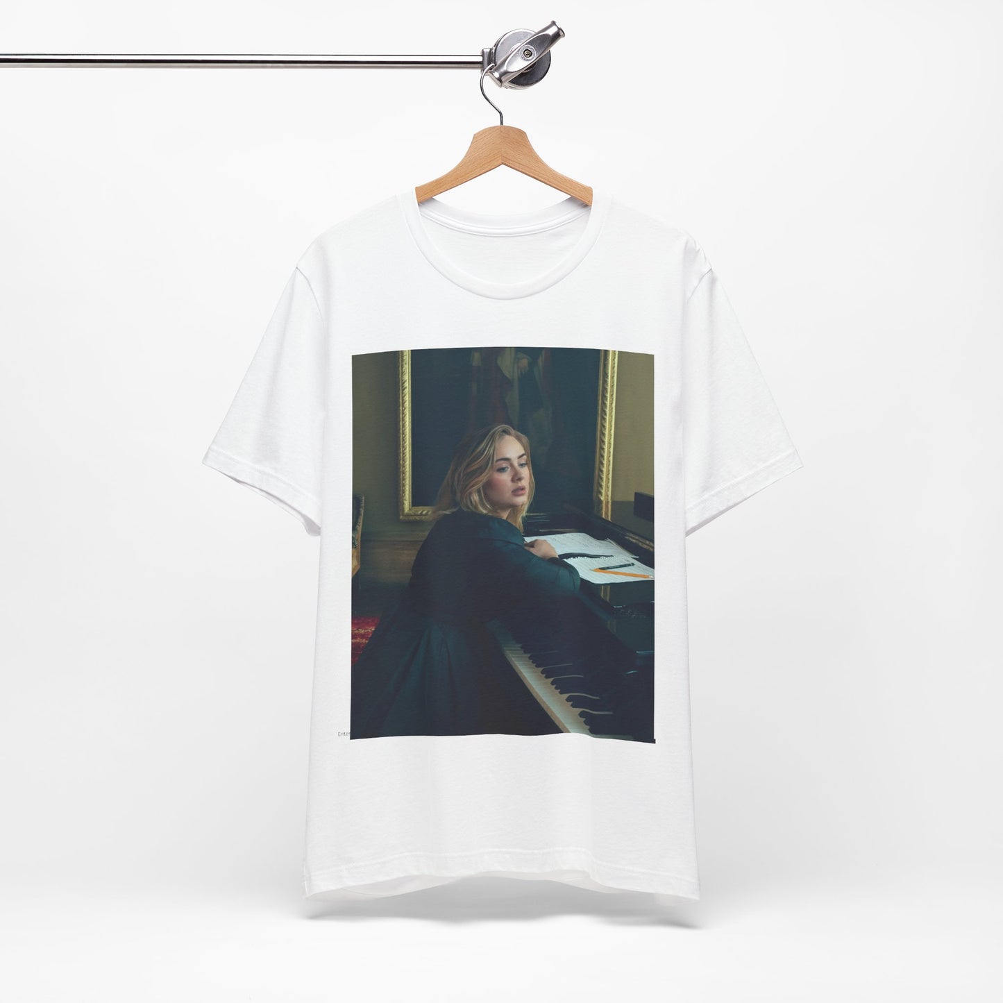 A black graphic t-shirt featuring a black and white photo of Adele sitting at a piano, with a focused and emotional expression as if performing.