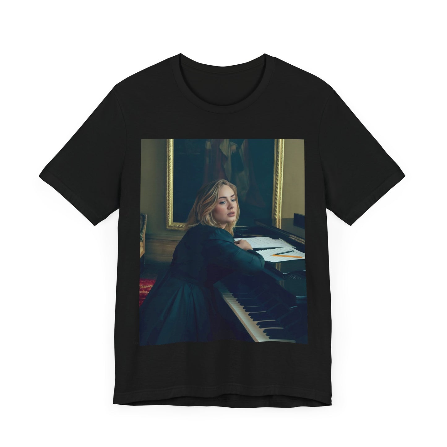A black graphic t-shirt featuring a black and white photo of Adele sitting at a piano, with a focused and emotional expression as if performing.