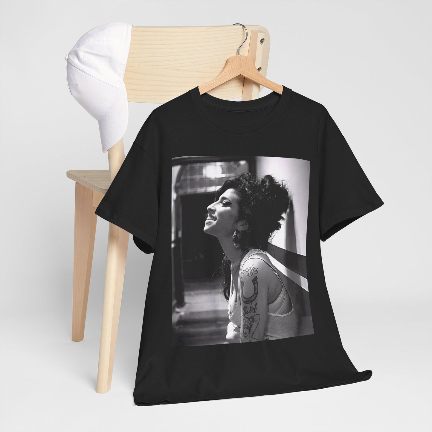 A black graphic t-shirt featuring a candid backstage photo of Amy Winehouse from her 'Back to Black' era, showing her in a relaxed setting.