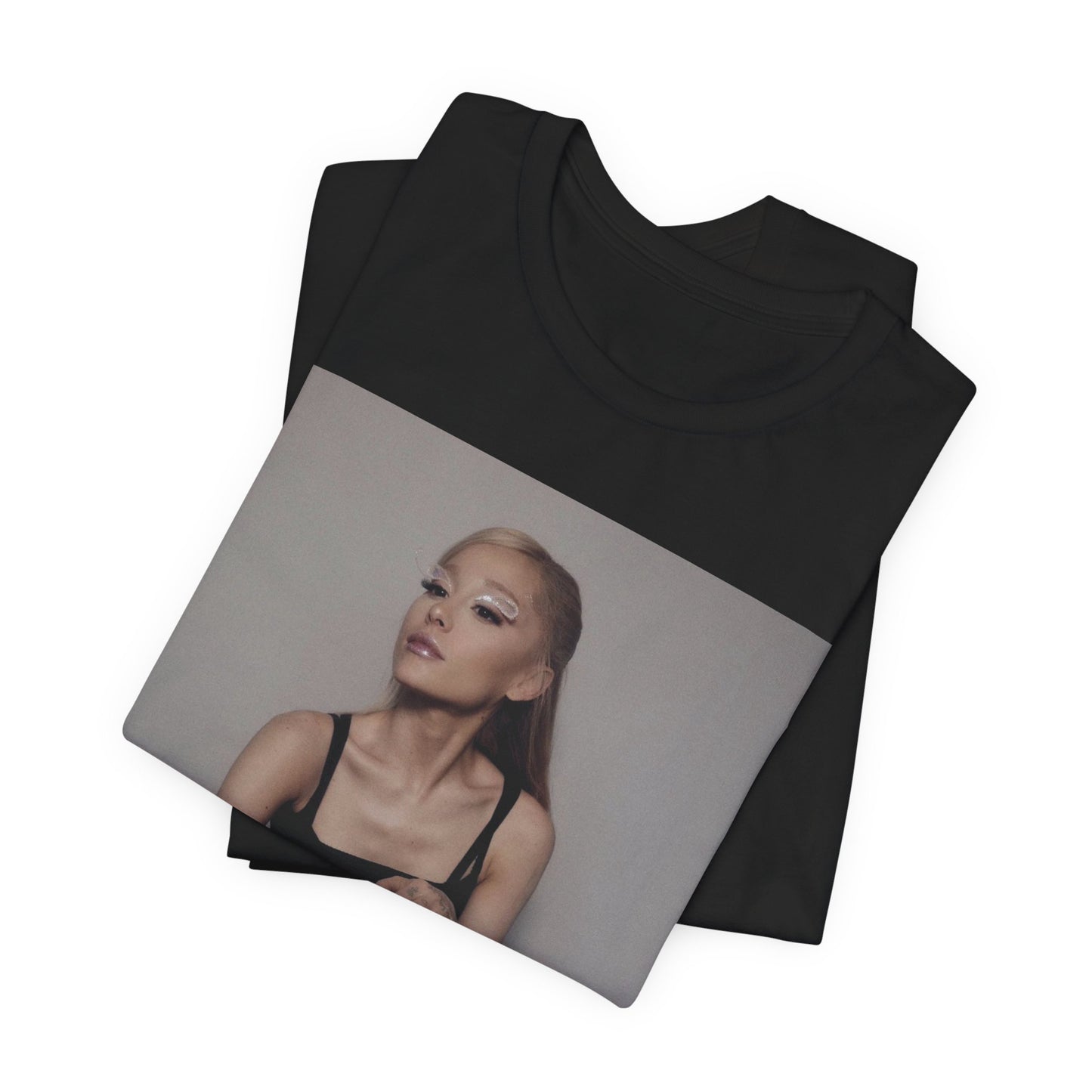 A black graphic t-shirt featuring a bold and beautiful graphic of Ariana Grande, emphasizing her strong and confident presence.