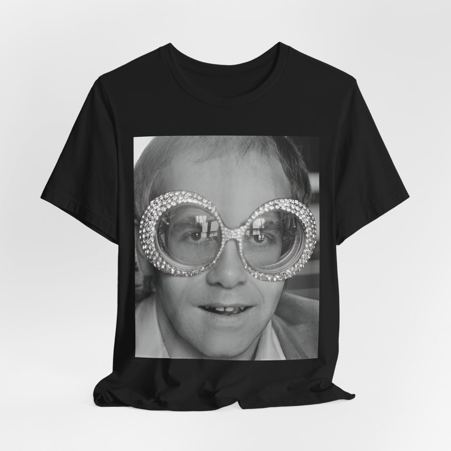 A black graphic t-shirt featuring a graphic of Elton John emphasizing his iconic glasses and fashion.
