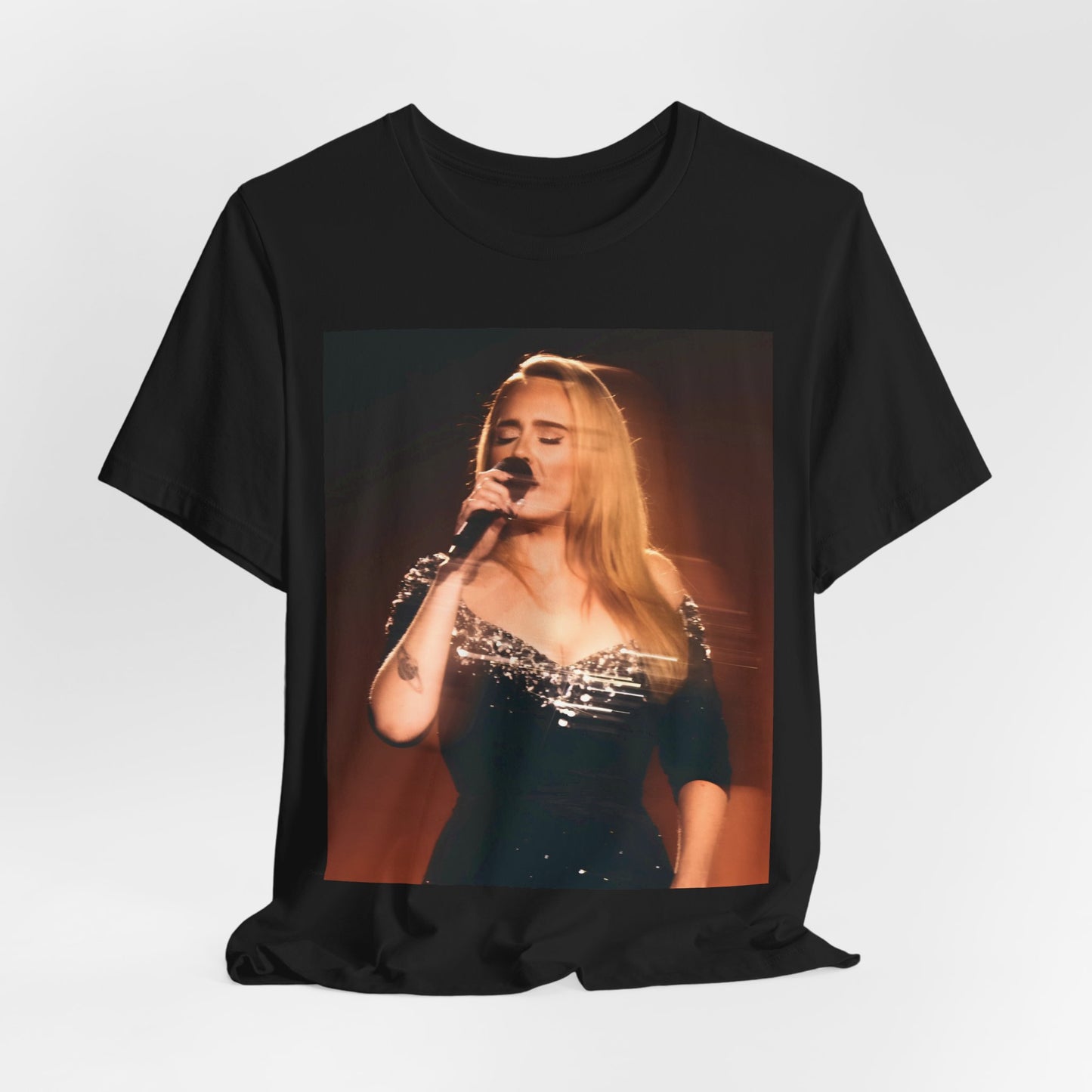 A black graphic t-shirt featuring a stylized image or photo of Adele related to her Las Vegas residency, possibly with elements of stage lighting or show branding.