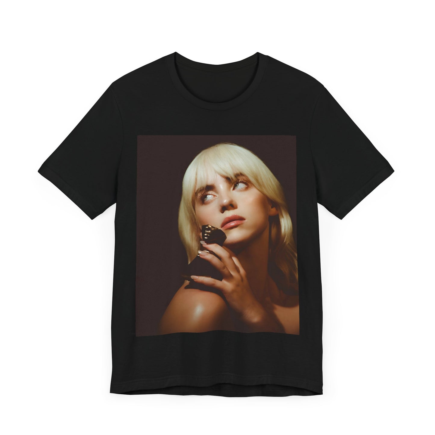 A soft, close-up portrait of Billie Eilish with dark hair looking down thoughtfully, printed on a graphic t-shirt.