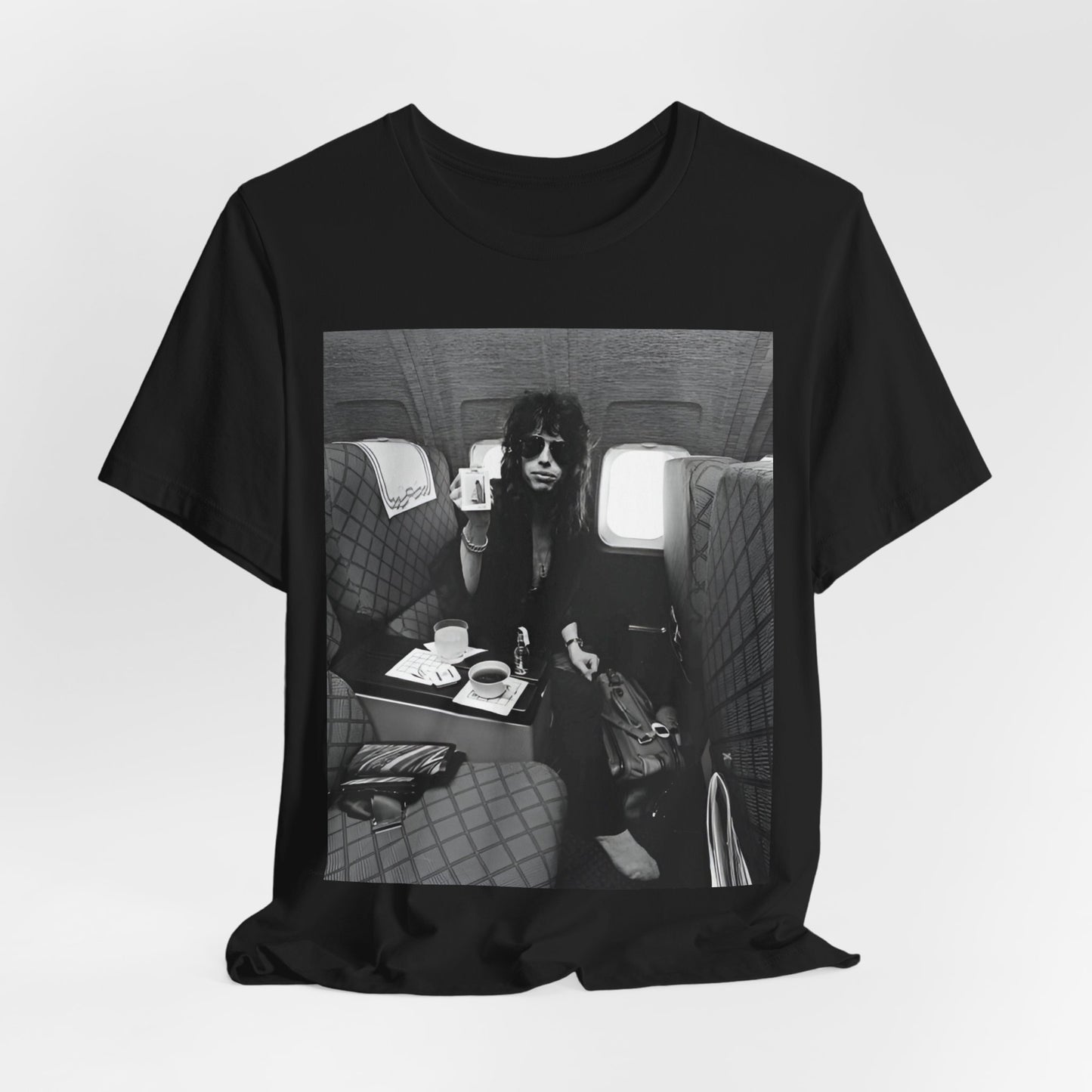 A black graphic t-shirt featuring a vintage 70s-style illustration of an airplane with Aerosmith branding, representing their tour plane from that era.