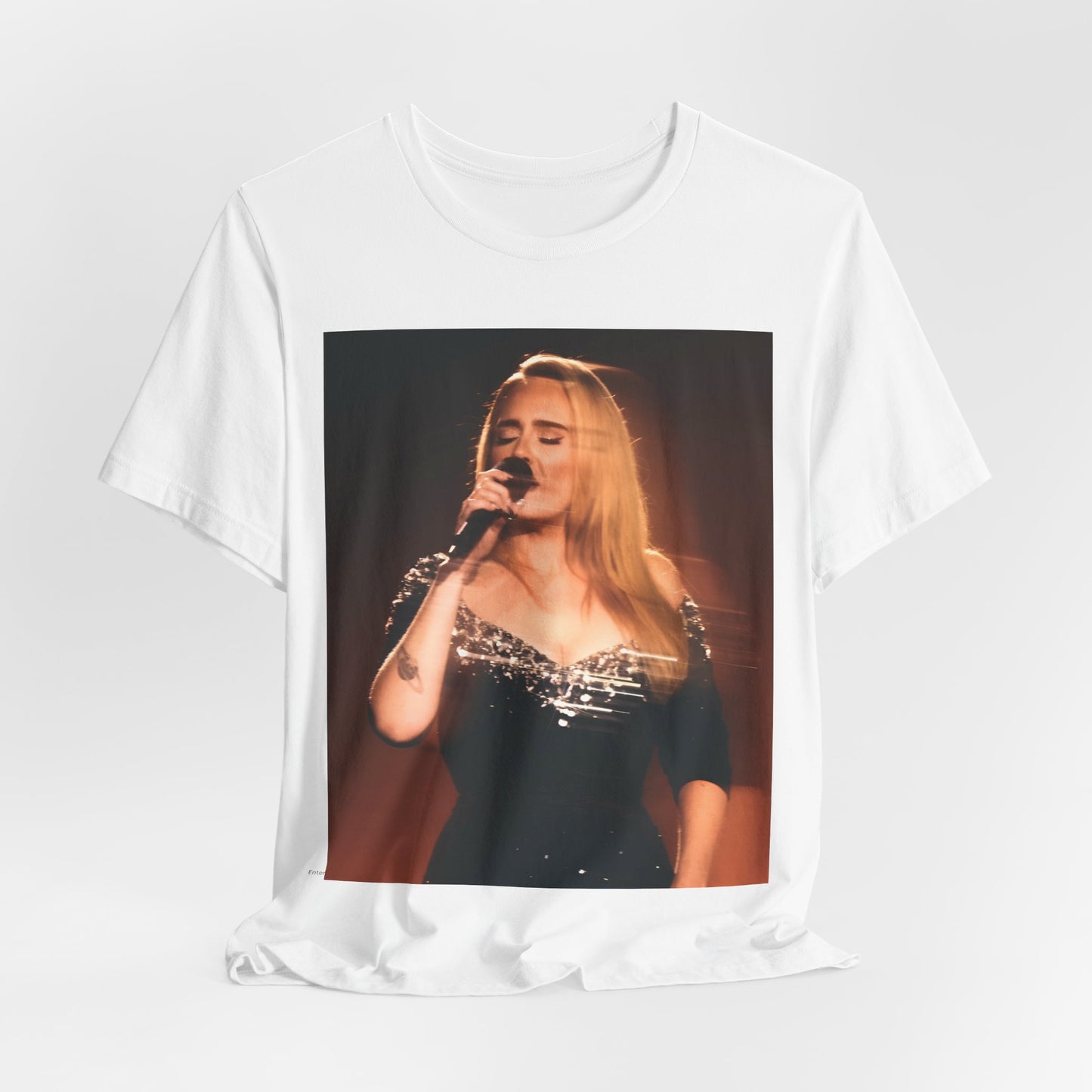 A black graphic t-shirt featuring a stylized image or photo of Adele related to her Las Vegas residency, possibly with elements of stage lighting or show branding.