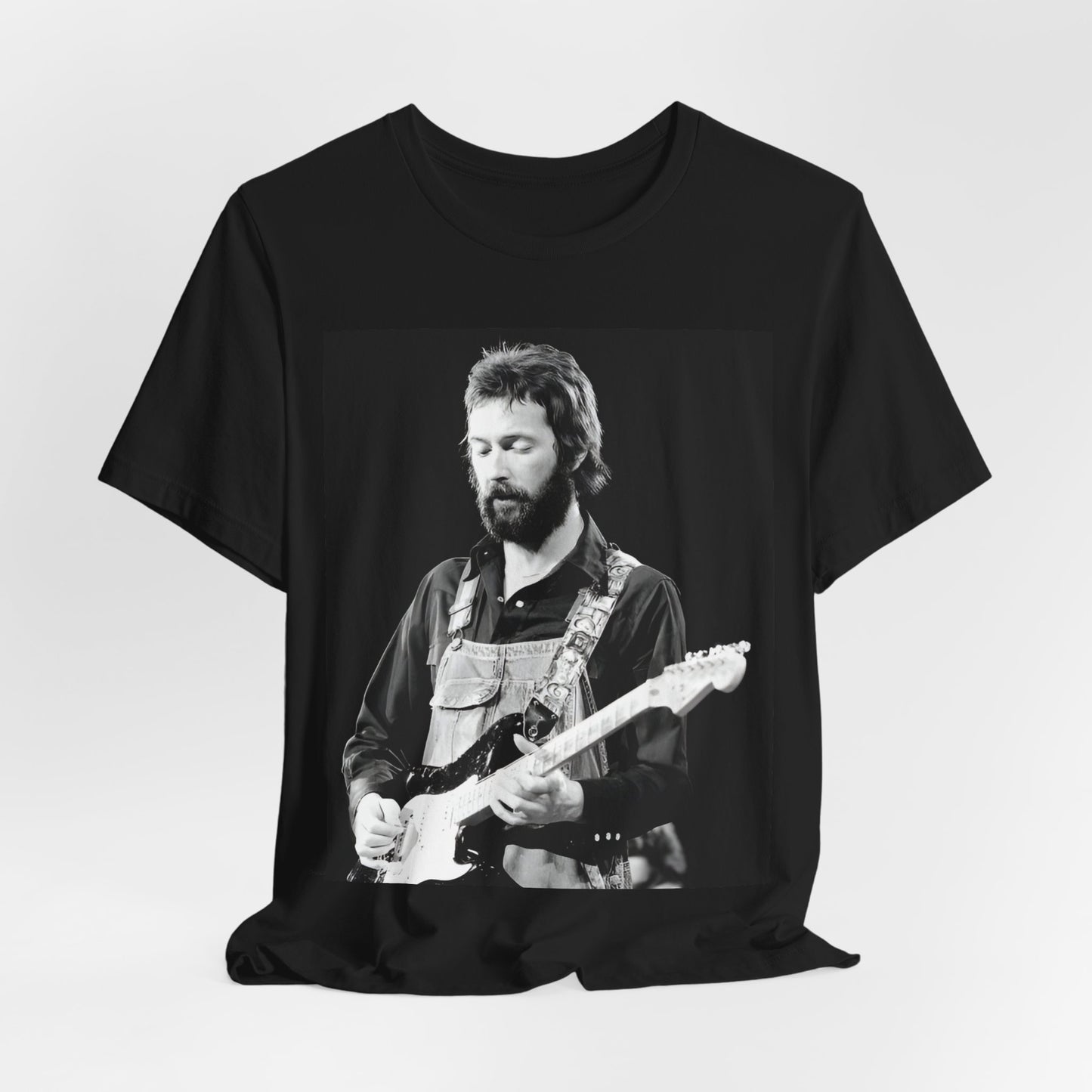 A black graphic t-shirt featuring a graphic or photo of Eric Clapton performing live on stage with his guitar.