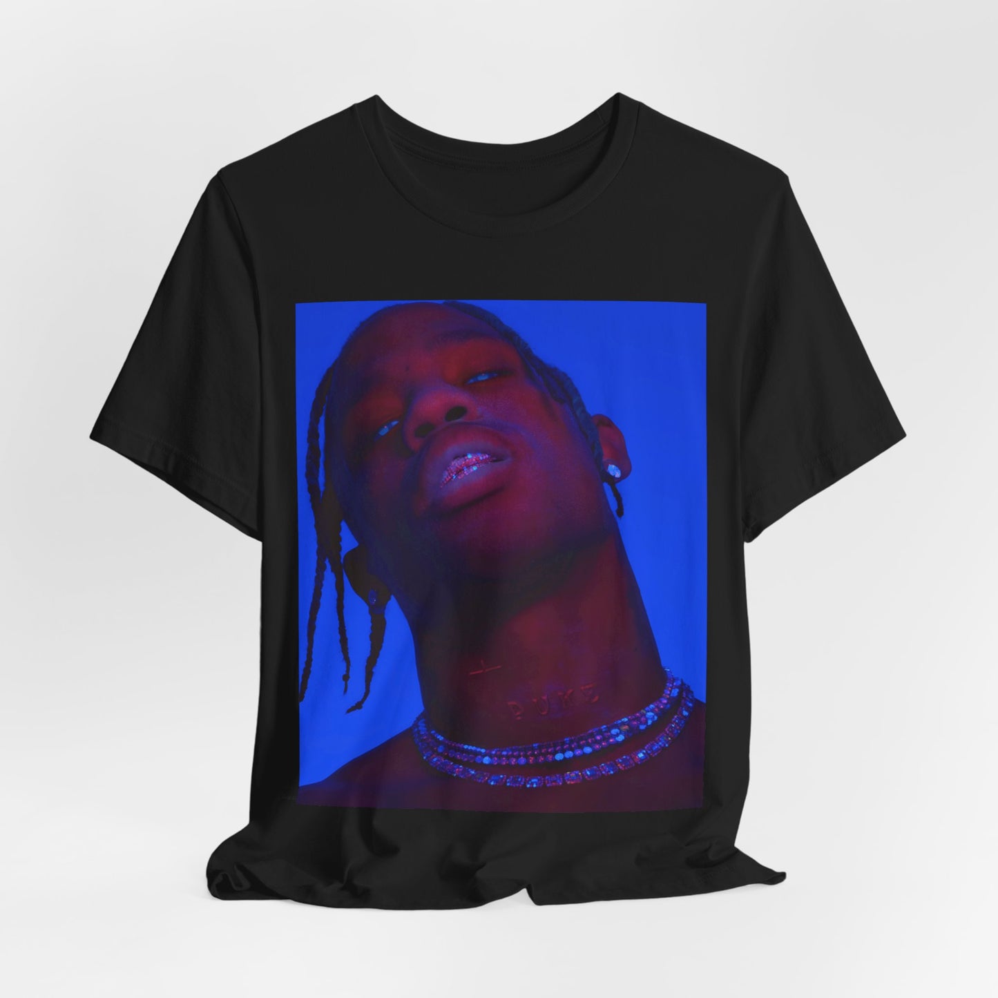 A black graphic t-shirt featuring a bold graphic of Travis Scott as a rap superstar.