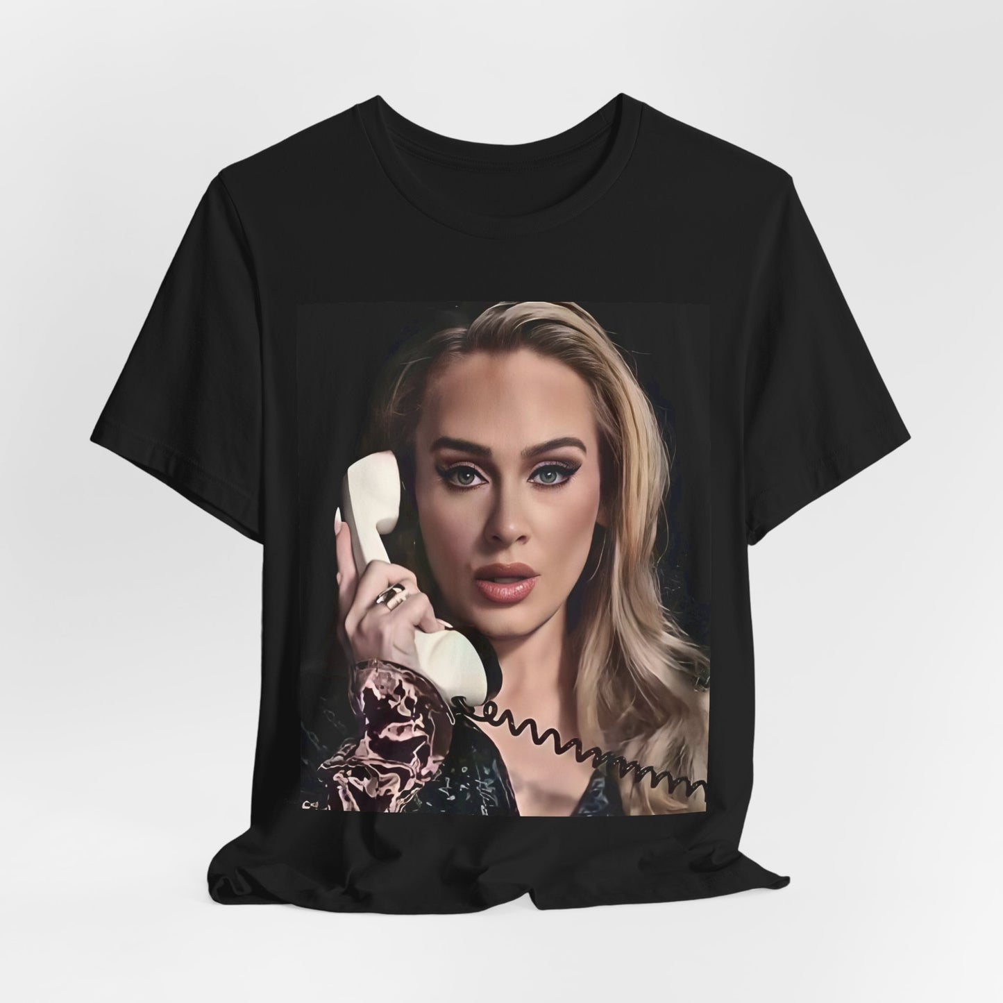 A black graphic t-shirt featuring a black and white candid photo of Adele with a phone to her ear, showing a thoughtful or emotional expression.