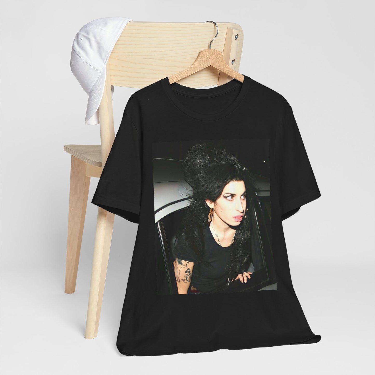 A black graphic t-shirt featuring a paparazzi-style photo of Amy Winehouse, showcasing her iconic look in a candid setting.