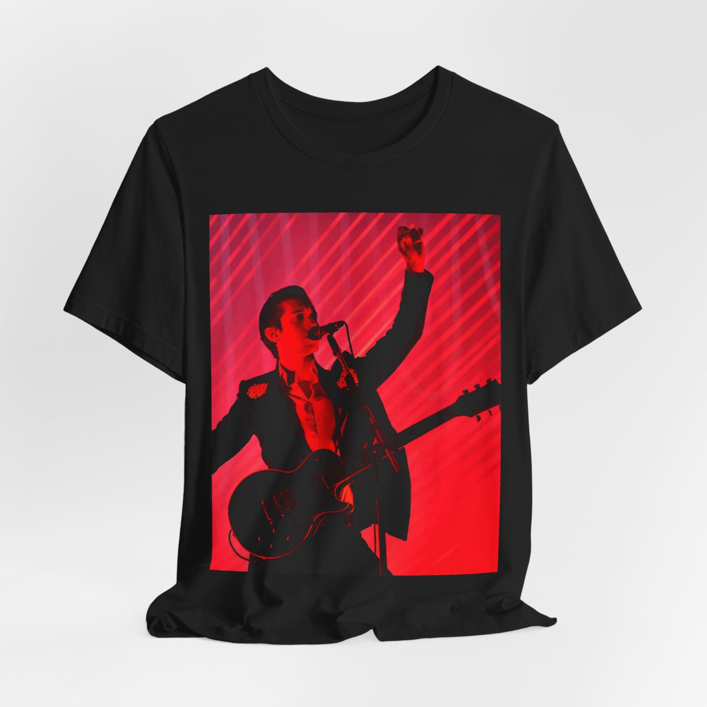 A black graphic t-shirt featuring a dynamic graphic or photo of Arctic Monkeys performing live in concert.