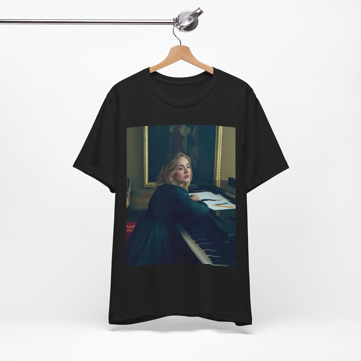 A black graphic t-shirt featuring a black and white photo of Adele sitting at a piano, with a focused and emotional expression as if performing.