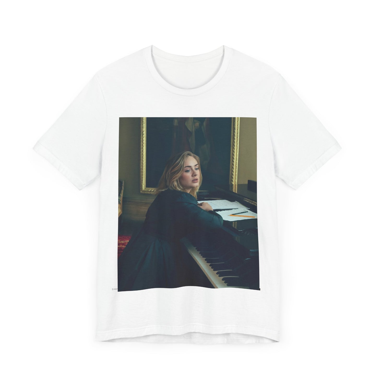 A black graphic t-shirt featuring a black and white photo of Adele sitting at a piano, with a focused and emotional expression as if performing.