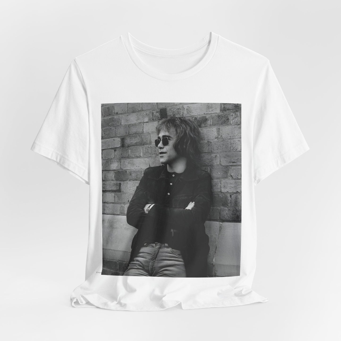 A black graphic t-shirt featuring a vintage graphic related to Elton John's 'Farewell Yellow Brick Road' tour.