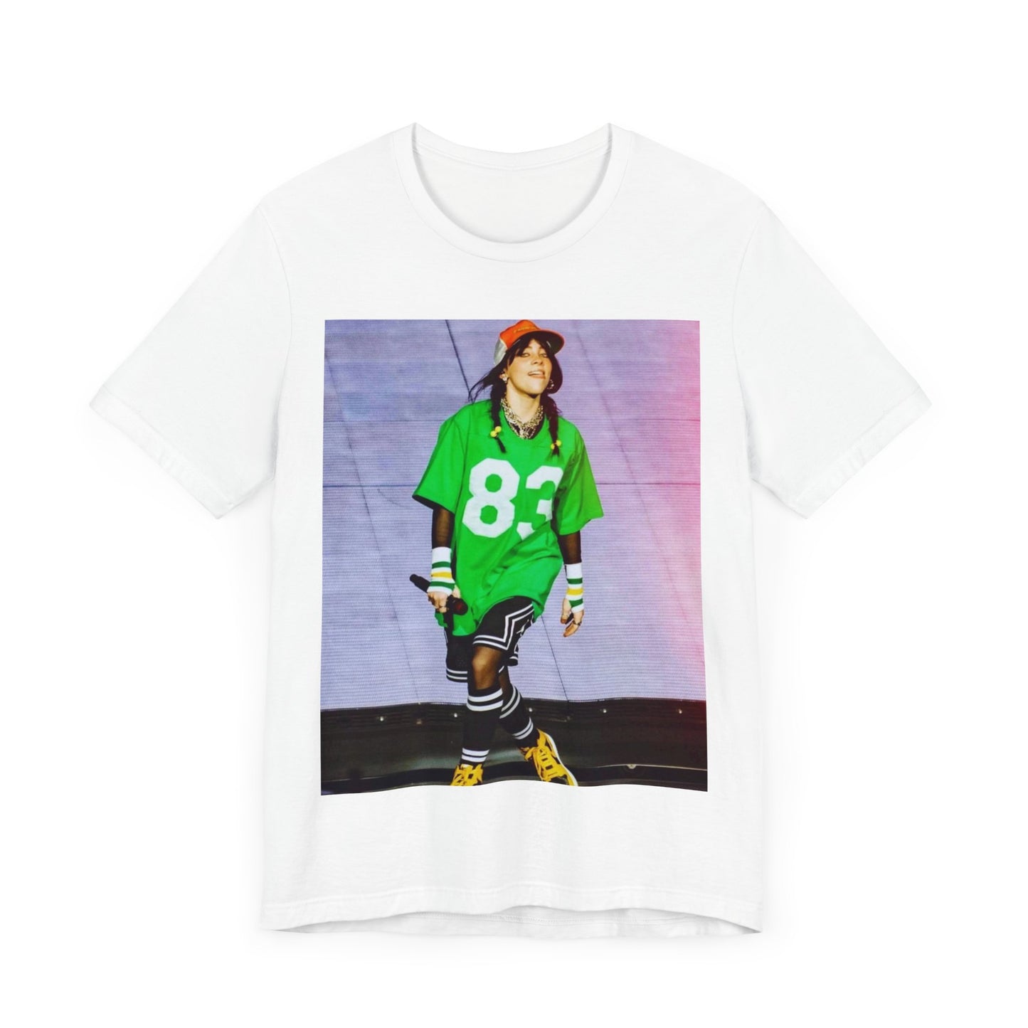 Billie Eilish performing on stage wearing a large green basketball jersey with the number 83 and an orange backwards cap.