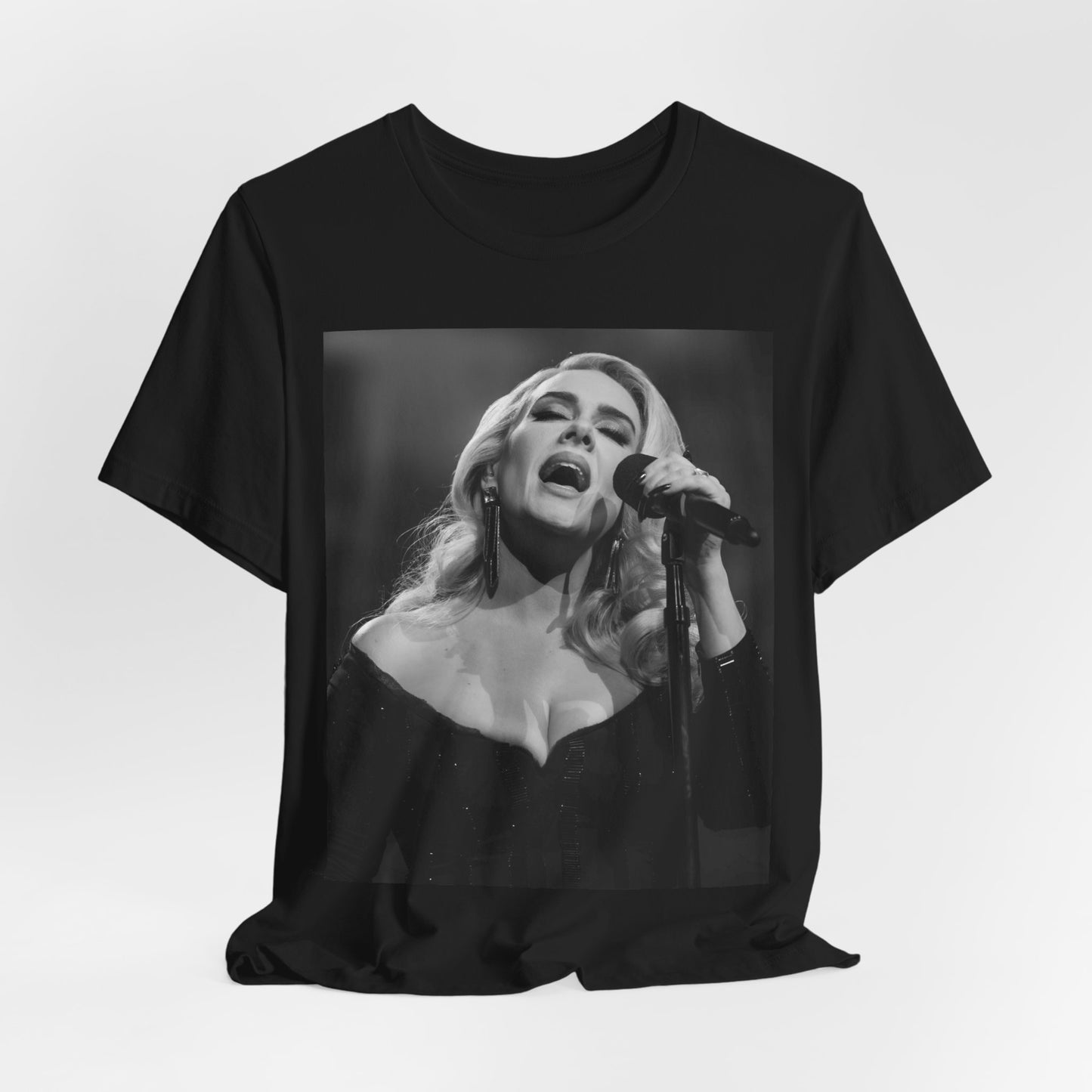 A black graphic t-shirt featuring a dynamic image of Adele performing on stage, with lighting effects, likely from her 'One Night Only' concert special.
