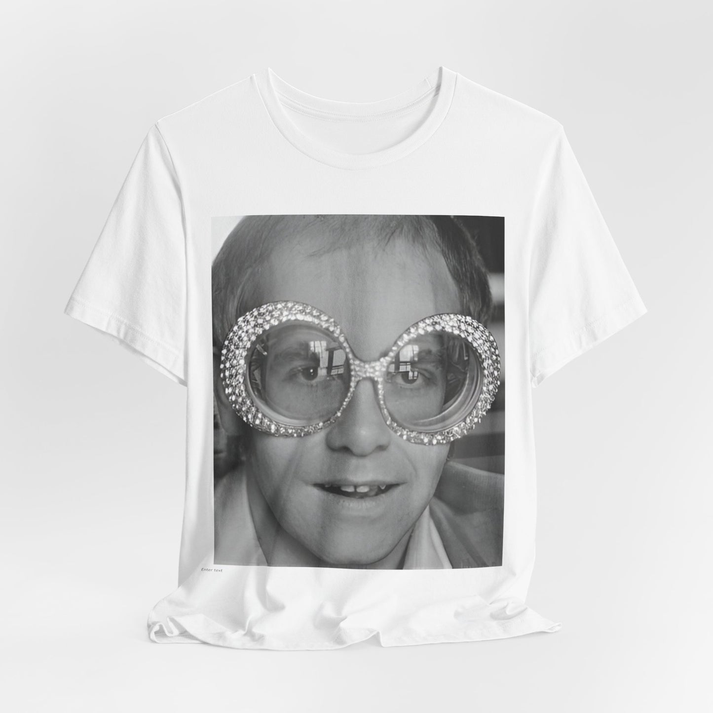 A black graphic t-shirt featuring a graphic of Elton John emphasizing his iconic glasses and fashion.