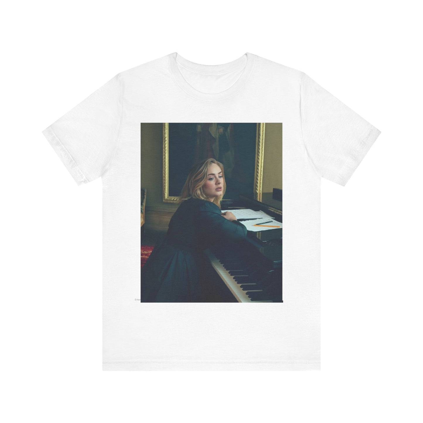 A black graphic t-shirt featuring a black and white photo of Adele sitting at a piano, with a focused and emotional expression as if performing.
