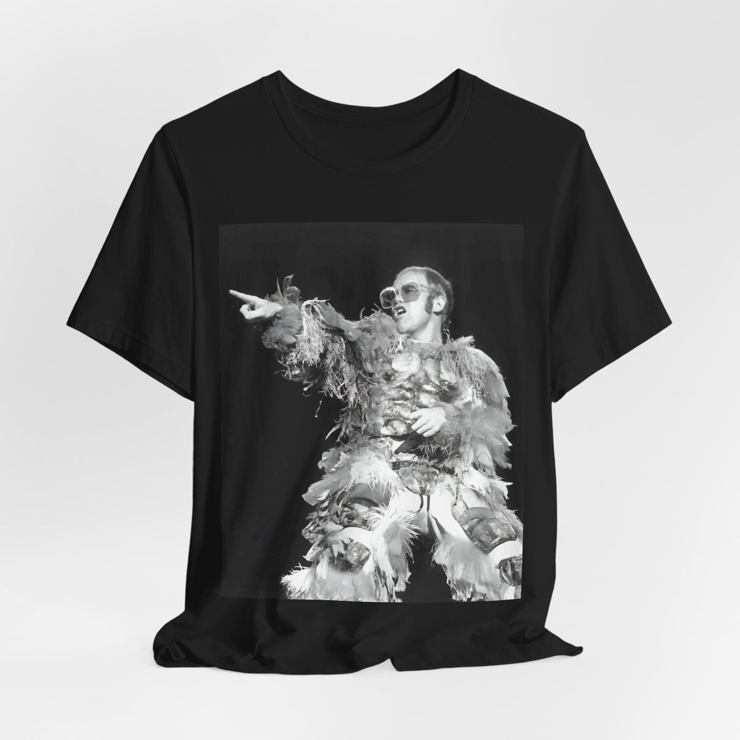 A black graphic t-shirt featuring a retro graphic of Elton John as a rock legend performing live.