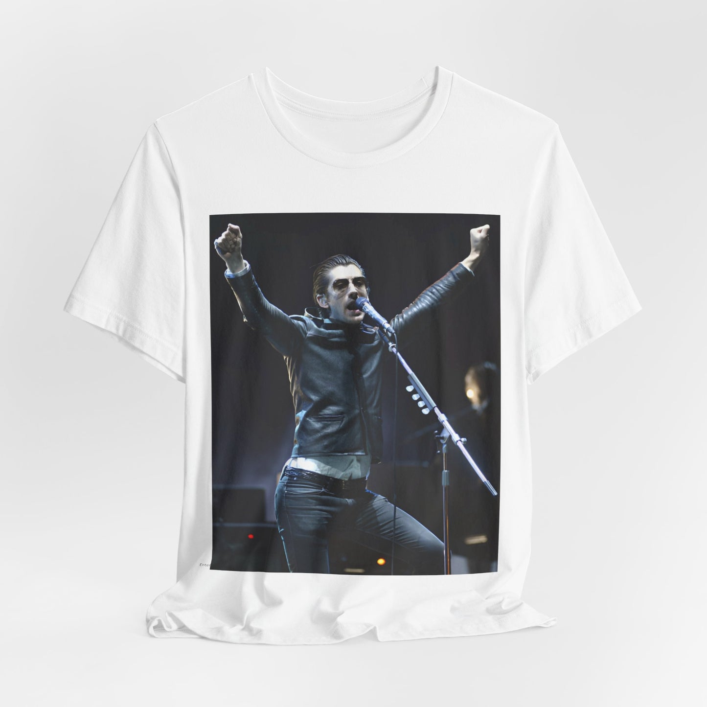 A black graphic t-shirt featuring a graphic or photo of Arctic Monkeys performing live on stage, with a Britpop aesthetic.