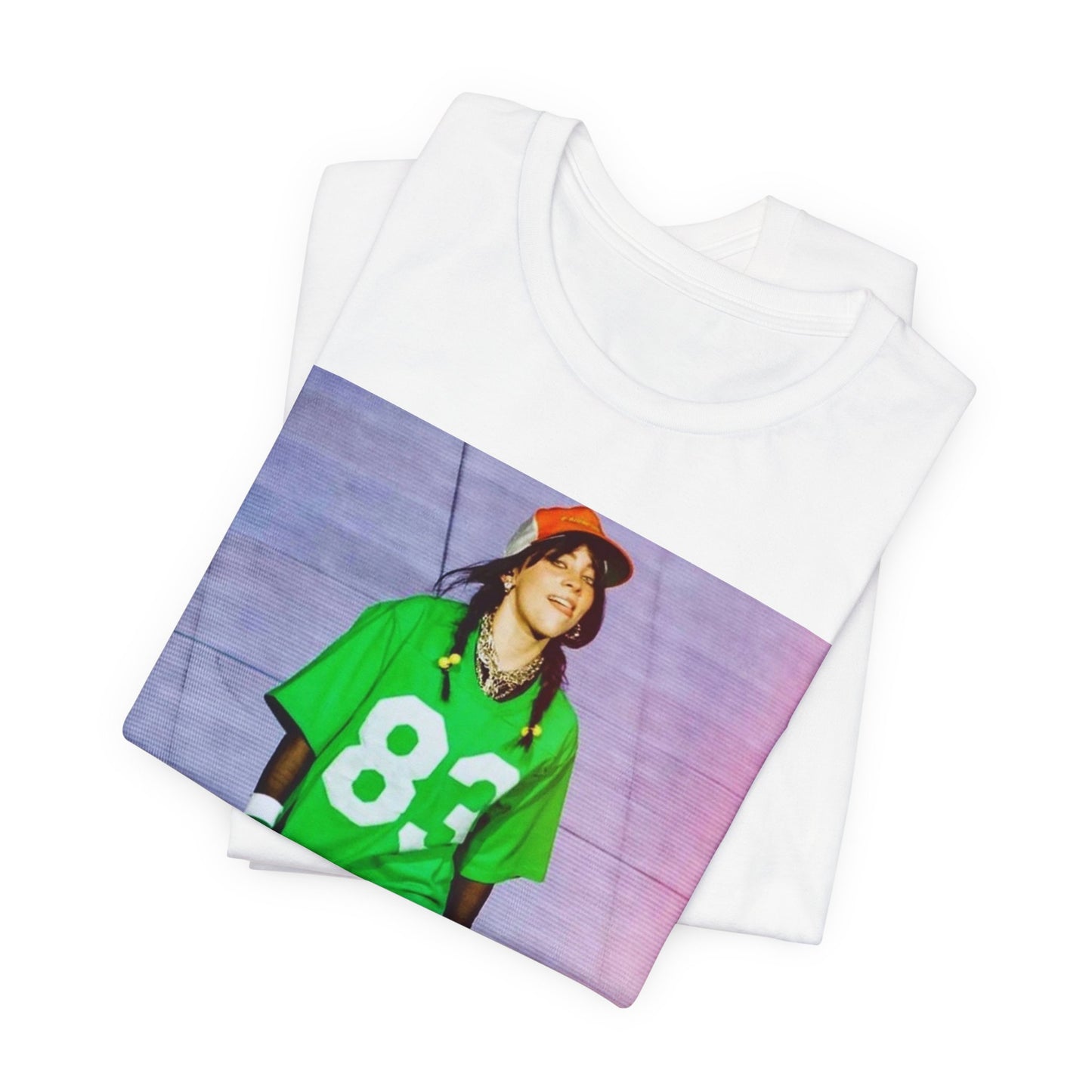 Billie Eilish performing on stage wearing a large green basketball jersey with the number 83 and an orange backwards cap.