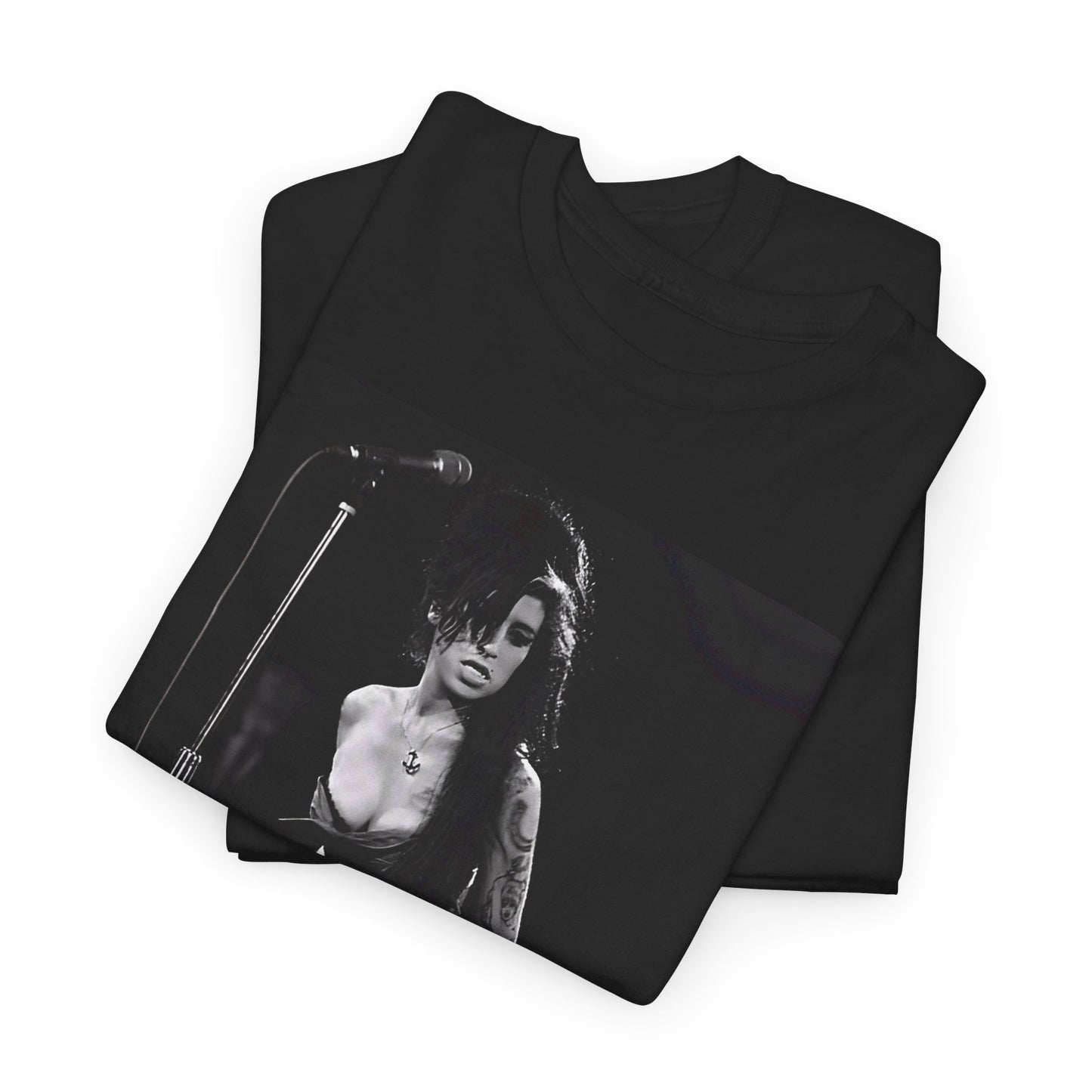 A black graphic t-shirt featuring a photo of Amy Winehouse performing live on stage at nightfall, with stage lighting effects.