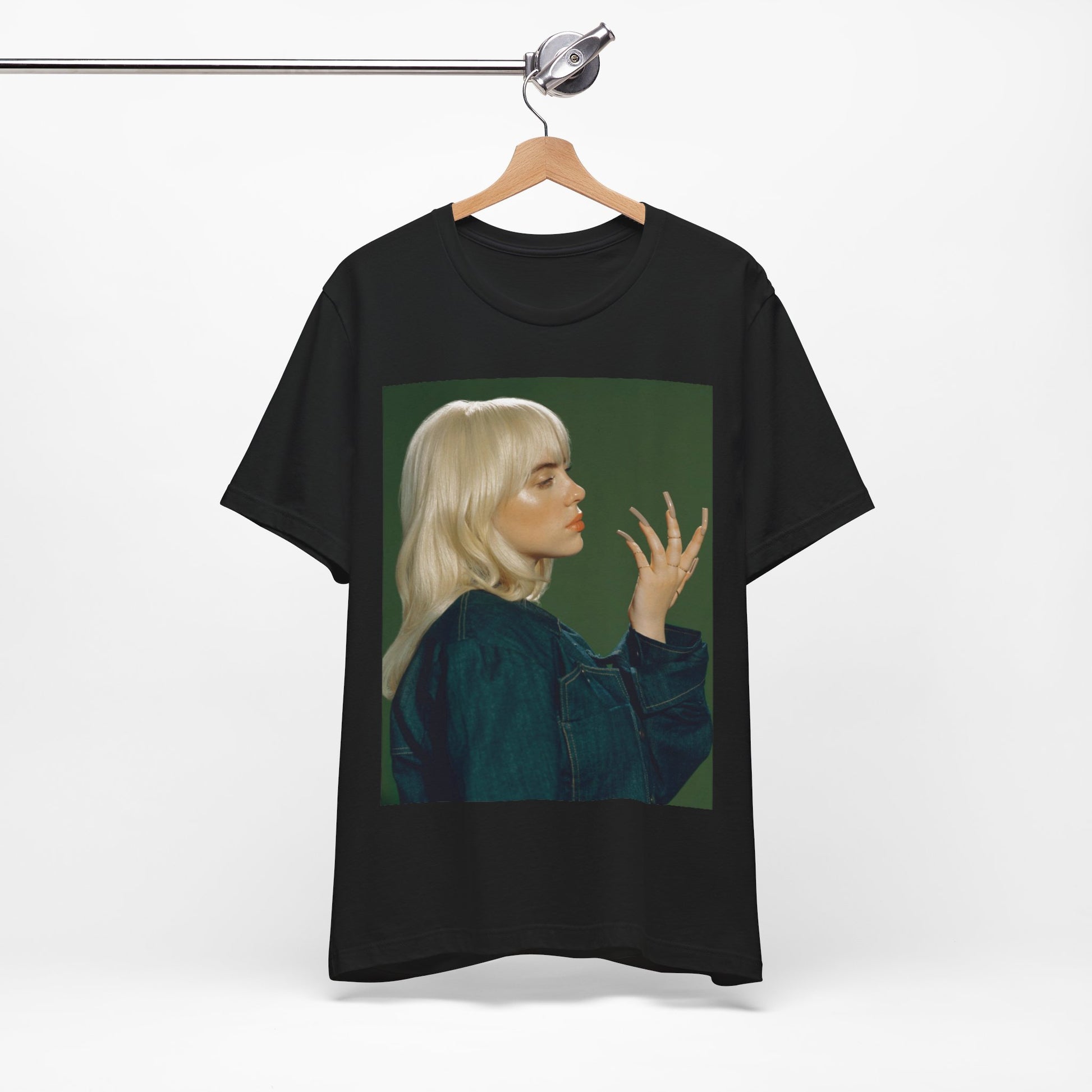 A vintage-style portrait of Billie Eilish with platinum blonde hair and long nails, wearing a denim jacket against a green background.