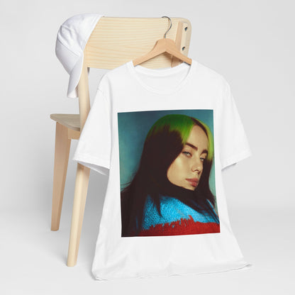 A close-up portrait of Billie Eilish with her signature green-root and black hair, wearing a blue and red sweater, printed on a graphic t-shirt.