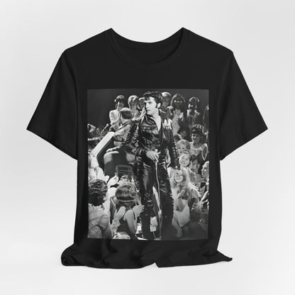 A black graphic t-shirt featuring a vintage black and white photo or graphic of Elvis Presley performing live on stage.