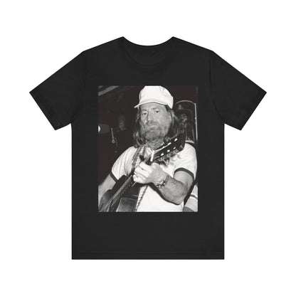 A black graphic t-shirt featuring a 70s cool free spirit graphic of Willie Nelson.