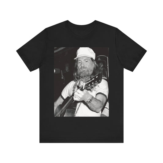 A black graphic t-shirt featuring a 70s cool free spirit graphic of Willie Nelson.