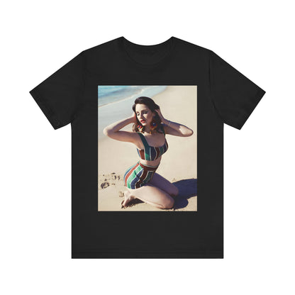 Lana Del Rey kneeling on a beach and posing in a vintage-style, high-waisted striped swimsuit, printed on a graphic t-shirt.