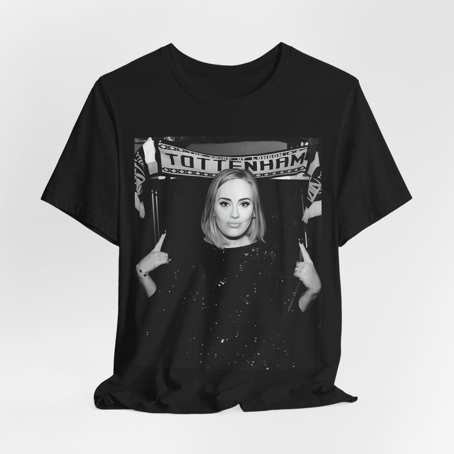 A black graphic t-shirt featuring a photo of Adele in a casual setting, surrounded by fans at a Tottenham event, showing her smiling or interacting.
