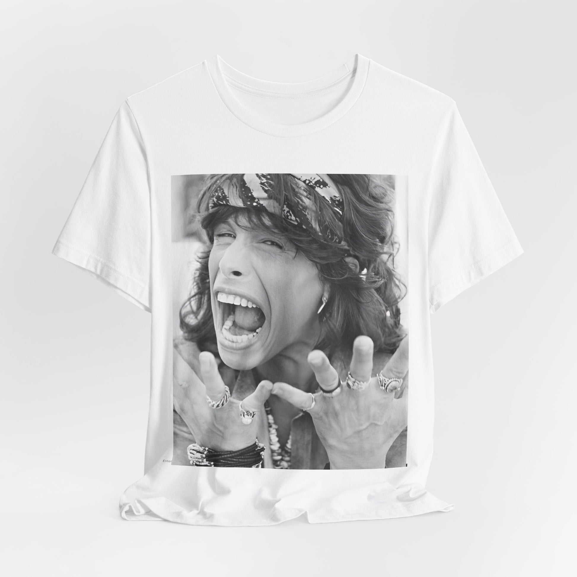 A black graphic t-shirt featuring a candid, dynamic photo of Aerosmith band members on tour in the 1970s, possibly showing action or interaction on stage or backstage.