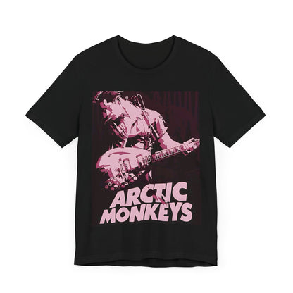 A black graphic t-shirt featuring the Arctic Monkeys logo in a prominent pink color, creating an aesthetic look.