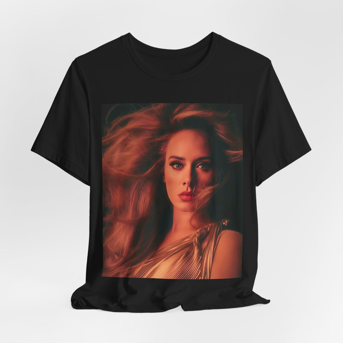 A black graphic t-shirt featuring a glamorous portrait of Adele wearing a golden gown, with voluminous hair, bathed in warm lighting, giving an editorial look.