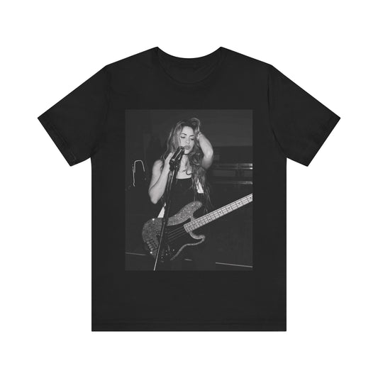 A black graphic t-shirt featuring a black and white graphic or photo of Shakira playing guitar live.