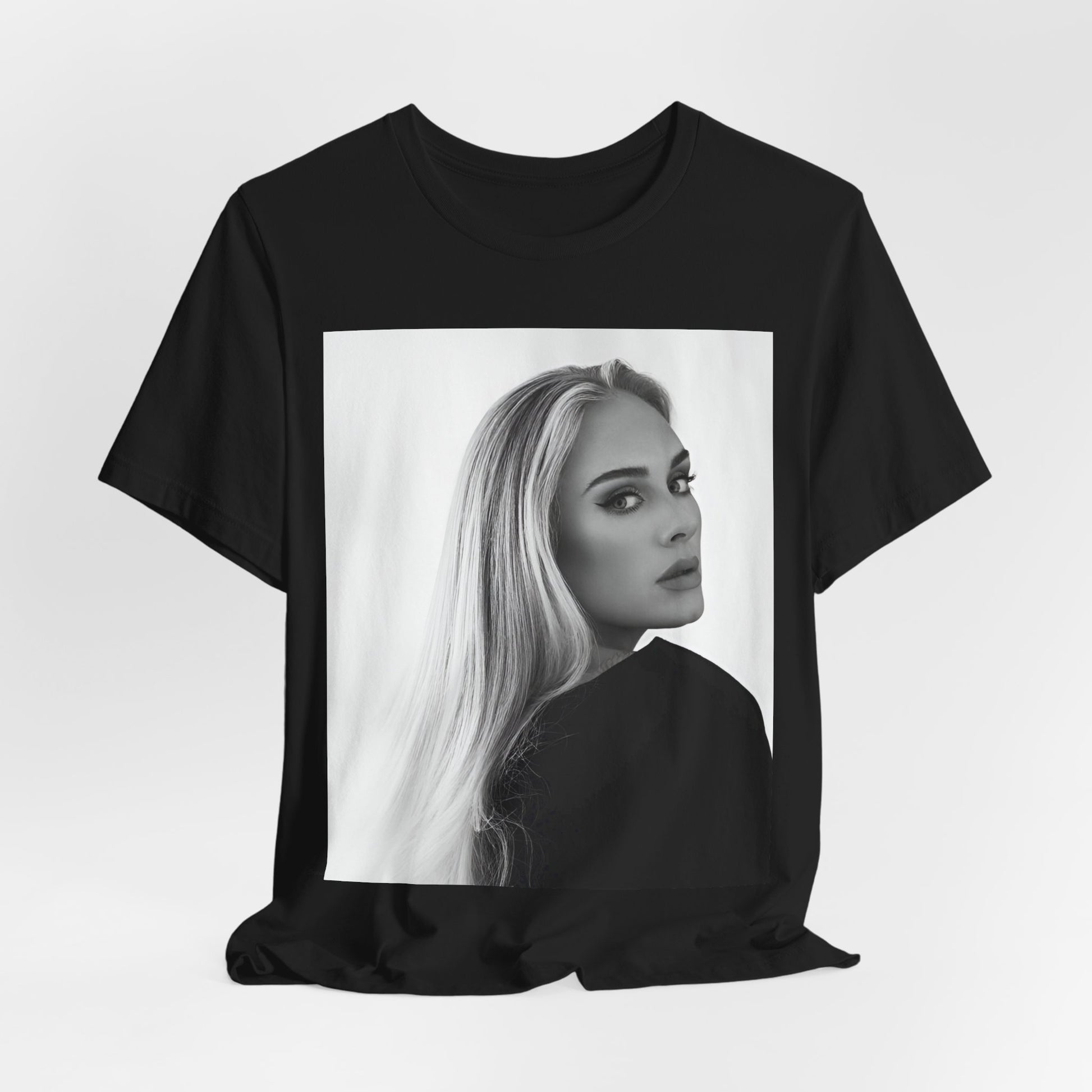 A black graphic t-shirt featuring a black and white, monochromatic portrait of Adele, showing her with a serene or thoughtful expression.