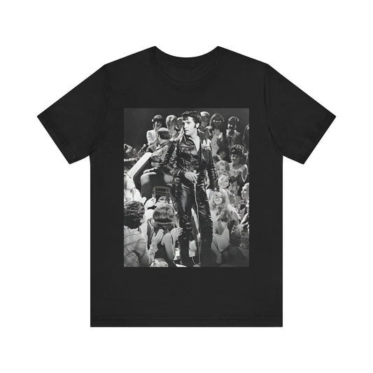 A black graphic t-shirt featuring a vintage black and white photo or graphic of Elvis Presley performing live on stage.