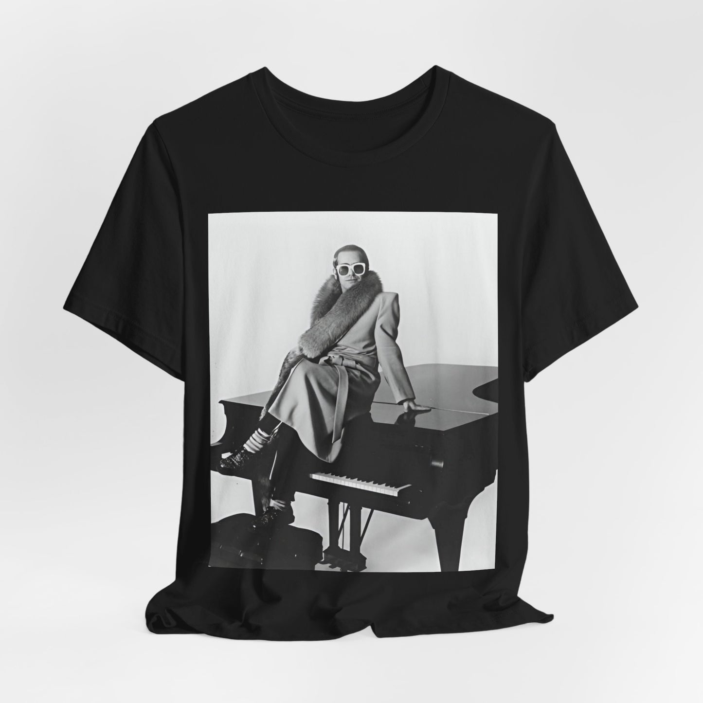 A black graphic t-shirt featuring a black and white photo of Elton John playing the piano.