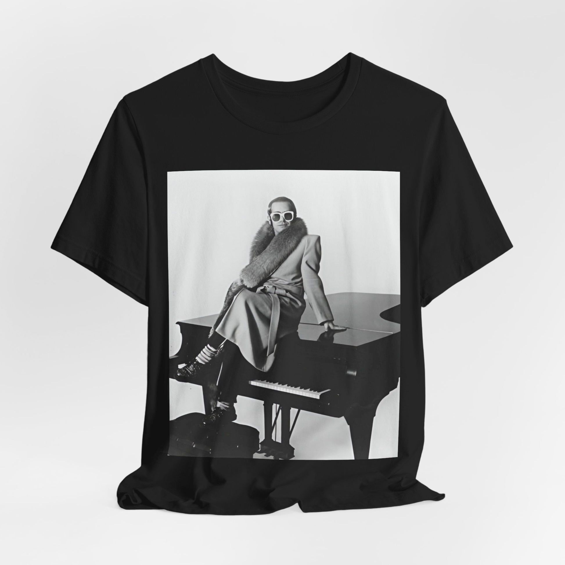 A black graphic t-shirt featuring a black and white photo of Elton John playing the piano.